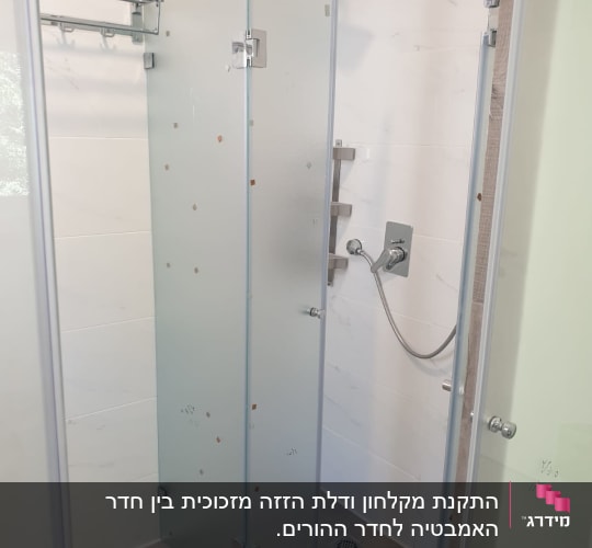 מקלחון זכוכית עם ראש מקלחת מרובע וקיר מתלה מגבות